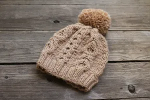 Knit beanie hat in beige color with cables and pom pom